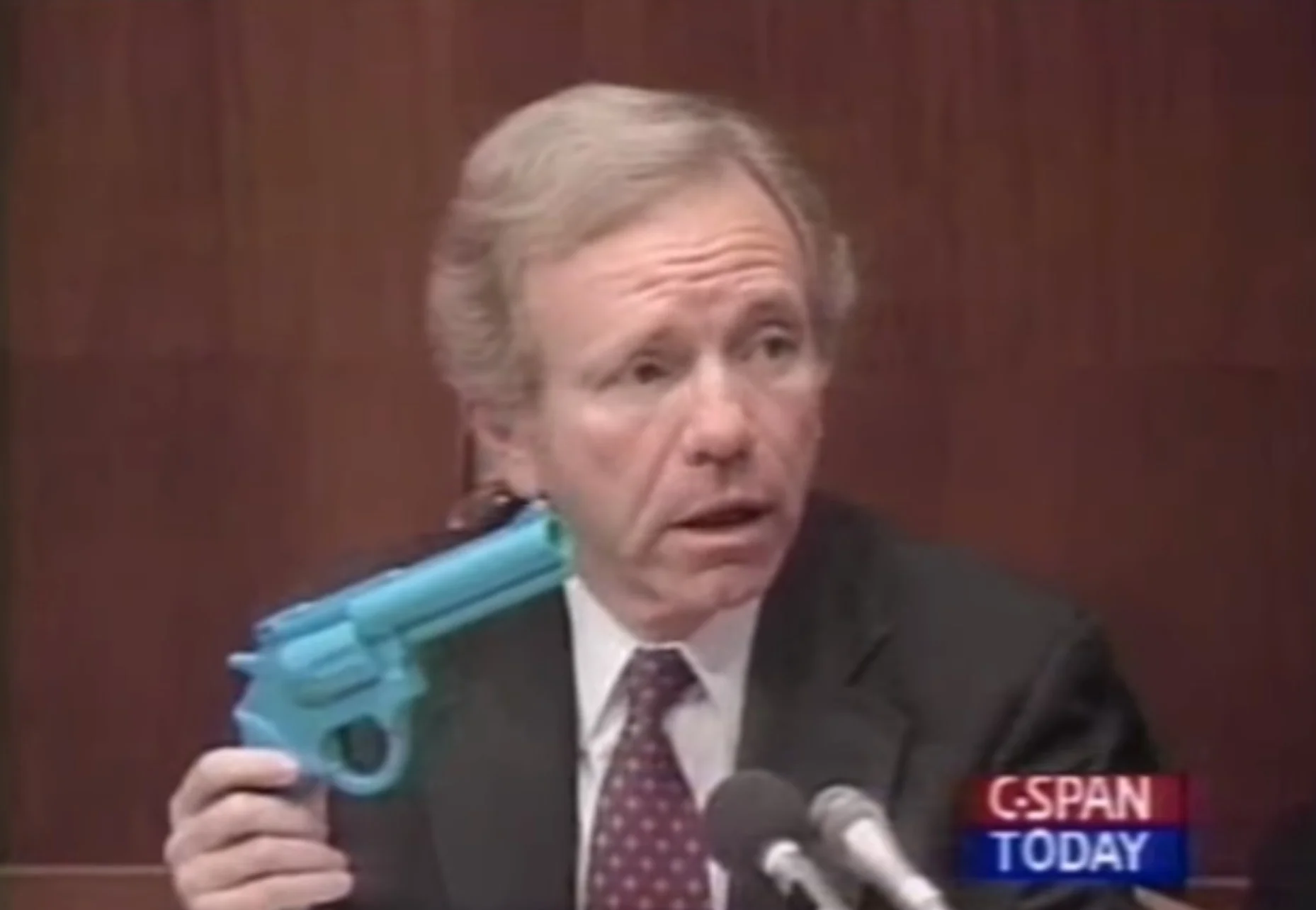 Джо Либерма показывает участникам пластмассовый световой пистолет на слушаниях 1993 года